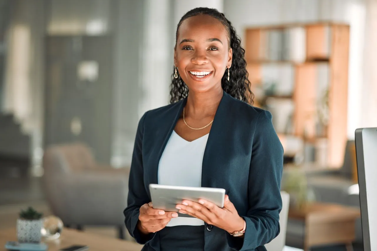Para quem serve o Adobe Acrobat Reader? | Foto de uma mulher negra jovem trabalhando no escritório e segurando um tablet | Assinatura Digital | Blog da Certisign